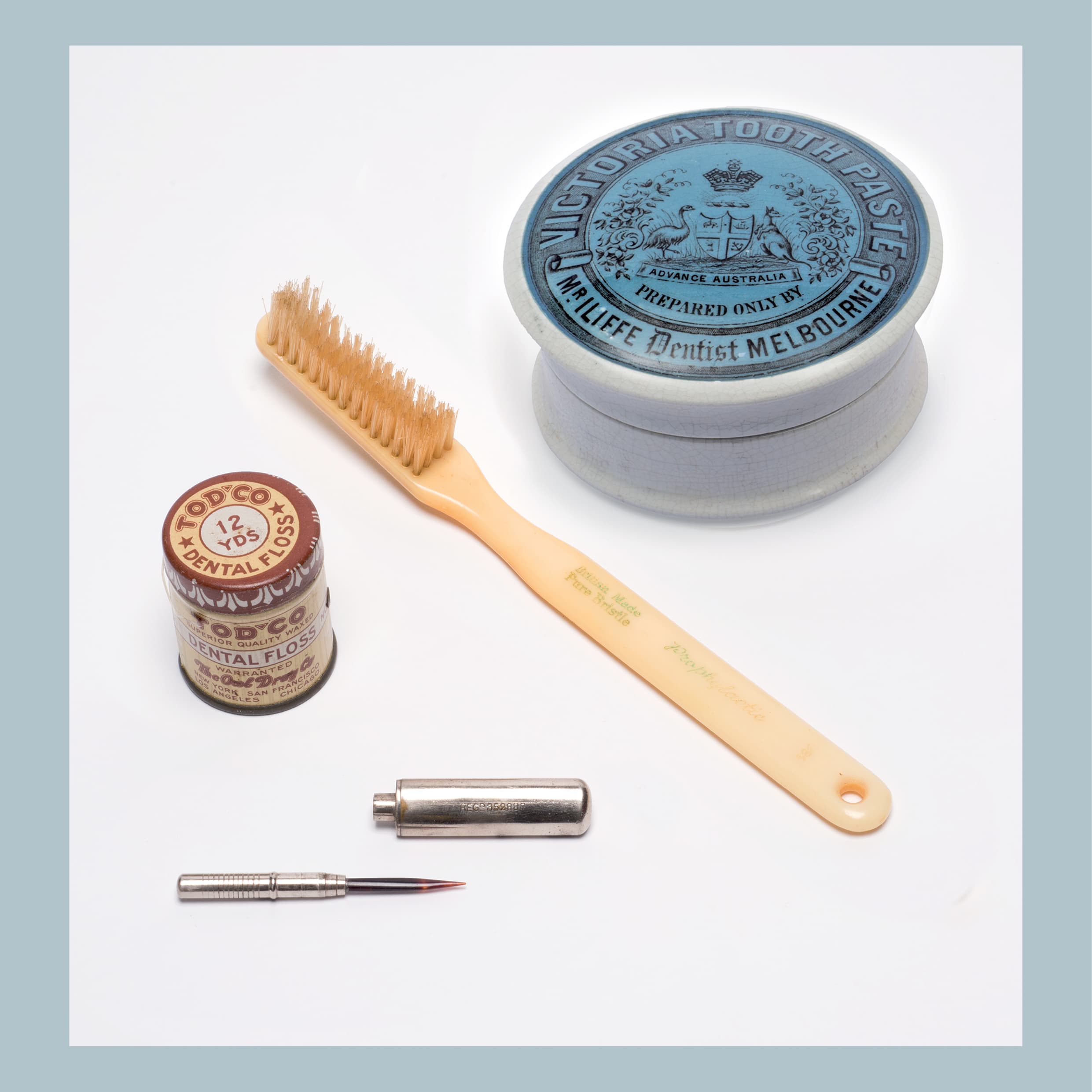 Clockwise from top:  John Iliffe (1846–1914), Victoria toothpaste jar, c. 1900, porcelain, 2.0 × 5.5 cm (diam.), HFADM 3146. Florence Manufacturing Company (Florence, Massachusetts, active 1866–1924), Toothbrush, 1910, bristle, plastic, 16.5 × 1.5 × 2.0 cm, HFADM 2128, gift of the Australian College of Dentistry 1963. Toothpick, c. 1890, brass, tortoiseshell, 6.0 × 1.0 cm (diam.), HFADM 784, gift of Jack Wunderly. The Owl Drug Company (USA, active 1892 – c. 1950), TOD’CO superior quality waxed dental floss, c. 1898, wood, steel, silk; 3.5 × 3.5 cm (diam.), HFADM 1094, gift of Dr Ian Chippendale on behalf of a patient c. 1990. All from Henry Forman Atkinson Dental Museum, University of Melbourne. 